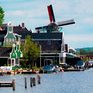 A coastal view of Kinderdijk, Netherlands, including traditional houses and a windmill in the land and seascape.