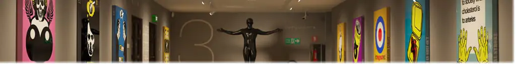 Interior of a museum, with paintings on the left and right walls, and a bronze sculpture in the center of a person.