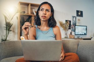 Woman sitting with a laptop, thinking.