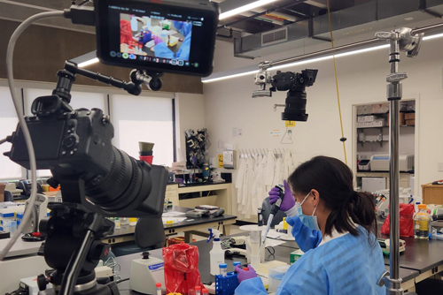 Student working in a lab filled with screens and video cameras.