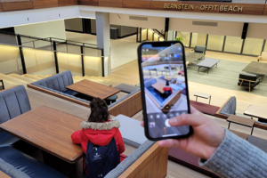 Someone holding a smartphone, taking a photo of a JHU student in the Hopkins Bloomberg Center in Washington, D.C. 