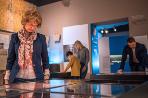 Museum patron looking at a glass display case in a museum.