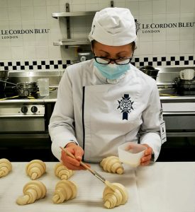 Kathryn Fisher brushing butter on croissants in a Le Cordon Bleu kitchen